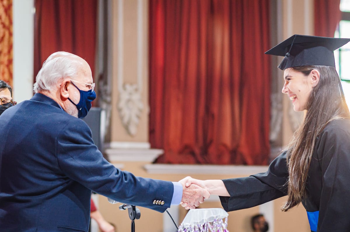 Formanda cumprimentando a autoridade da mesa ao receber o diploma