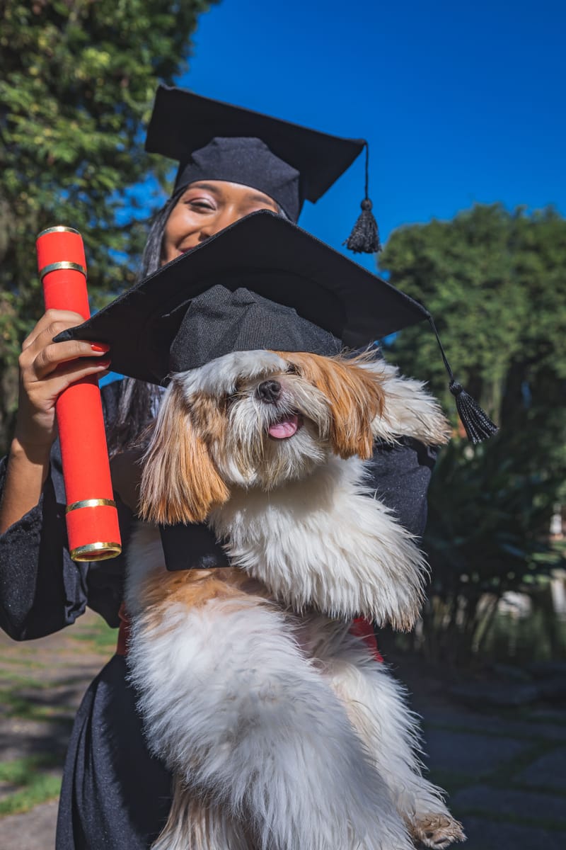 Formanda segurando o cachorro, que também está de capelo