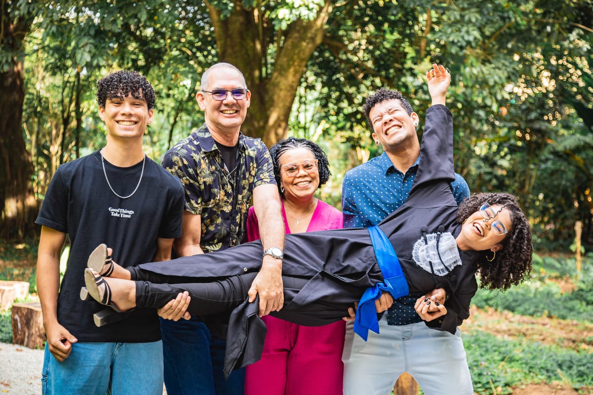 Família segurando a formanda no colo, todos rindo