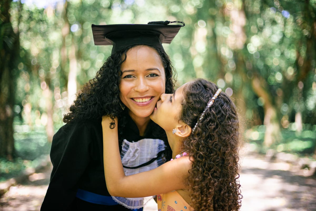 Formanda recebendo beijo de uma menina pequena