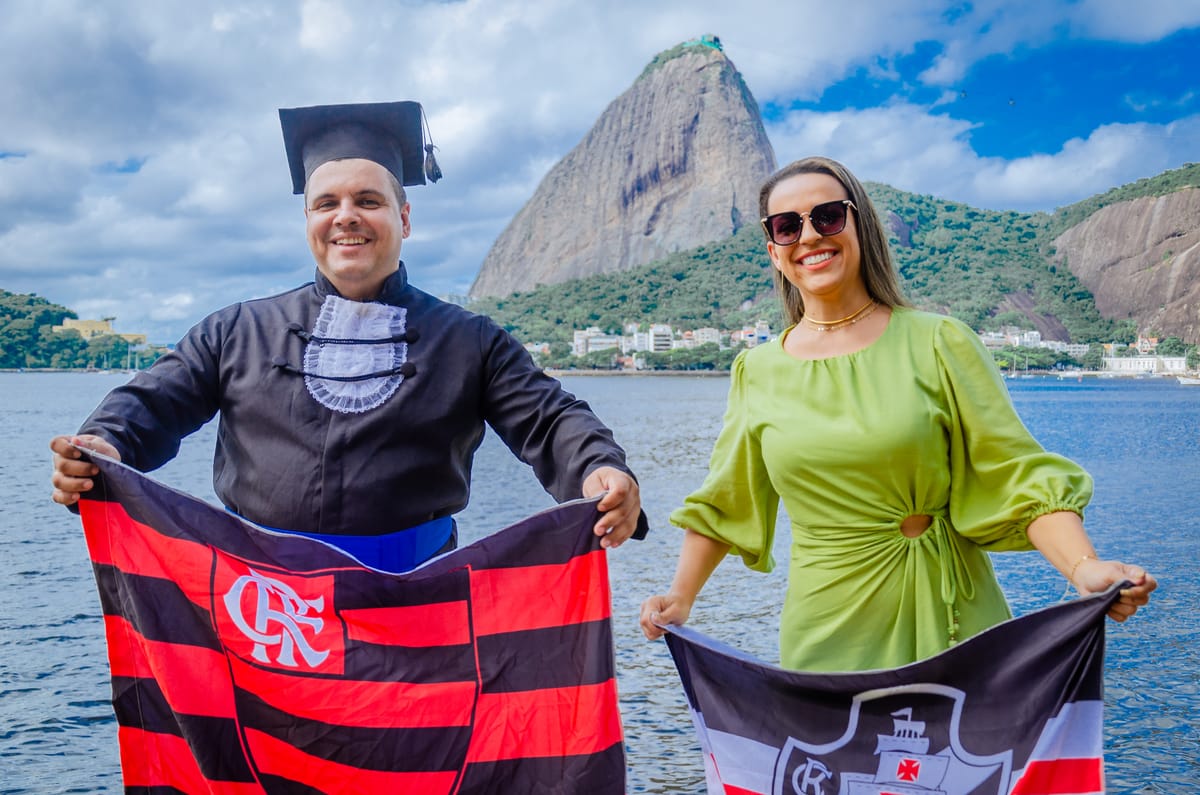 Formando e acompanhante com bandeiras de time diante do Pão de Açúcar