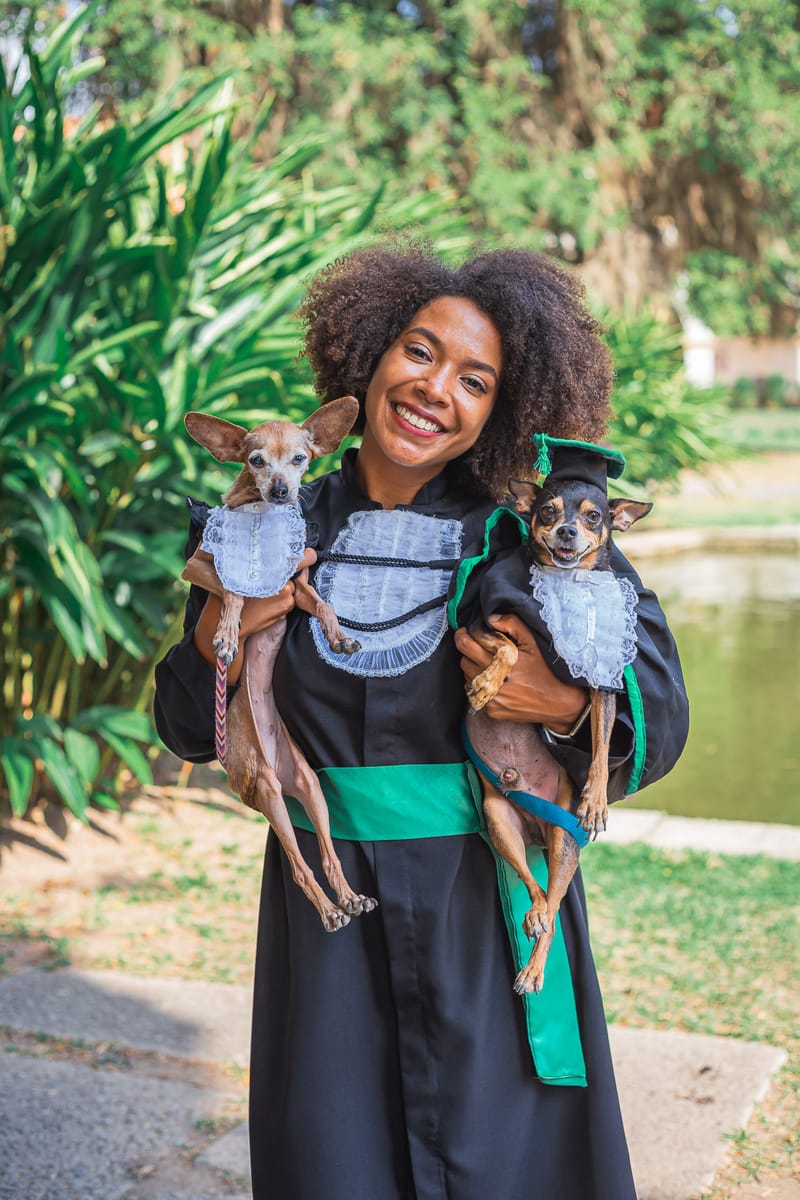 Formanda de beca segurando dois cachorrinhos