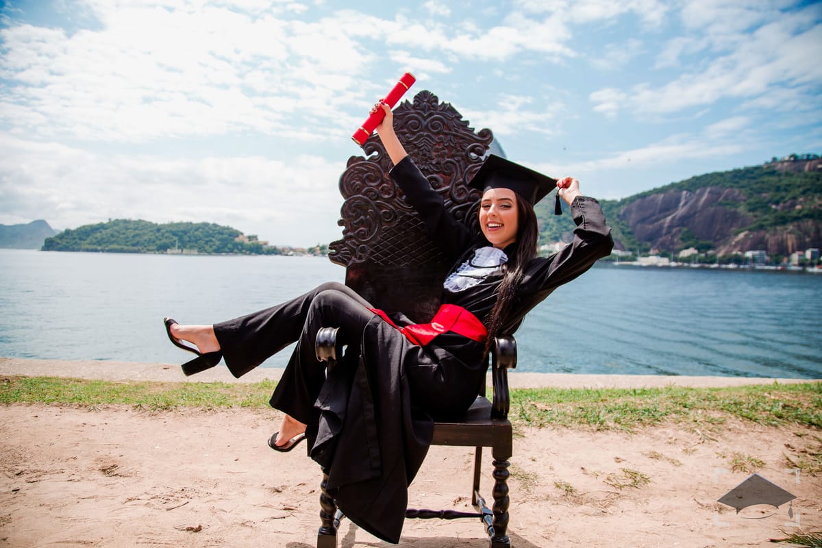 Formanda deitada na cadeira de formatura à beira-mar