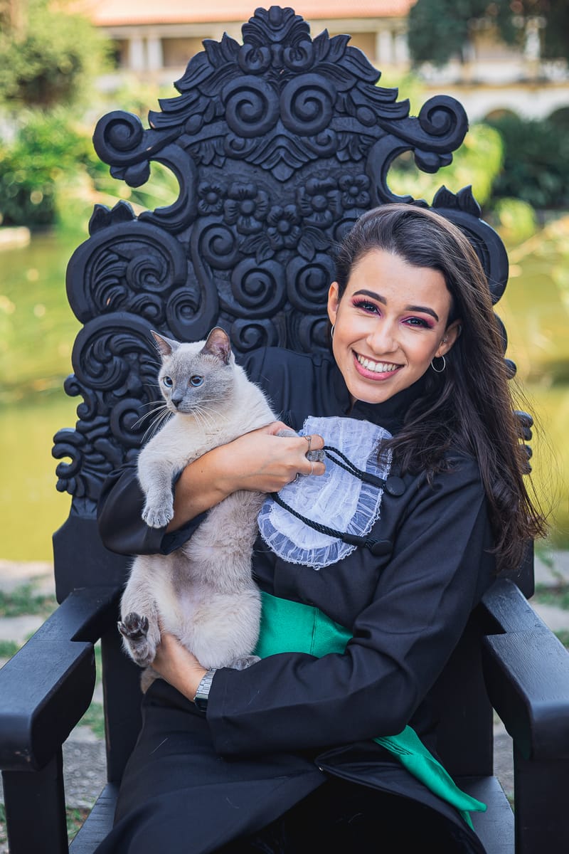 Formanda na cadeira de formatura com o gato no colo